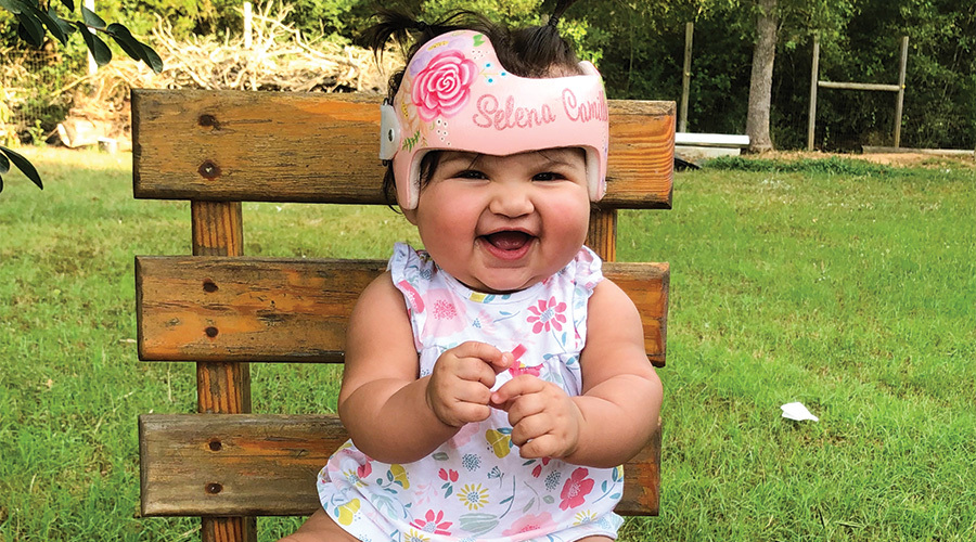 Little girl smiling in a doc band sitting on a bench