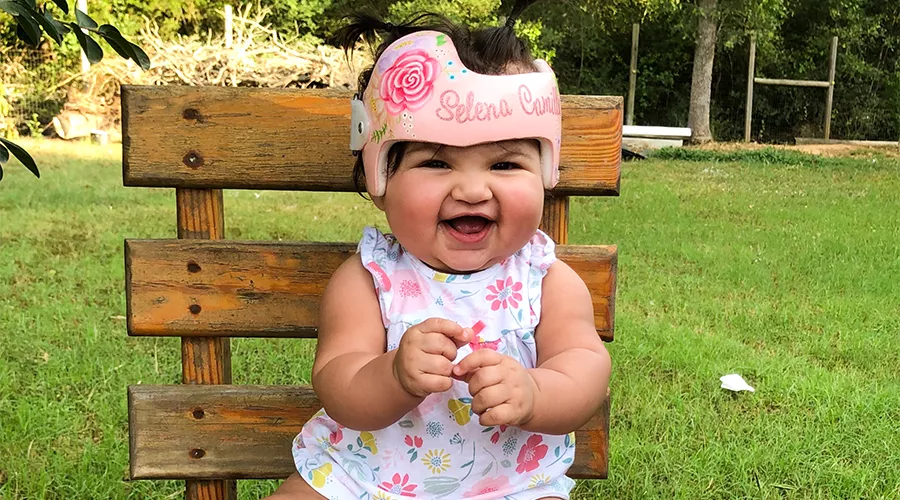 Baby girl smiling on a bench wearing a doc band